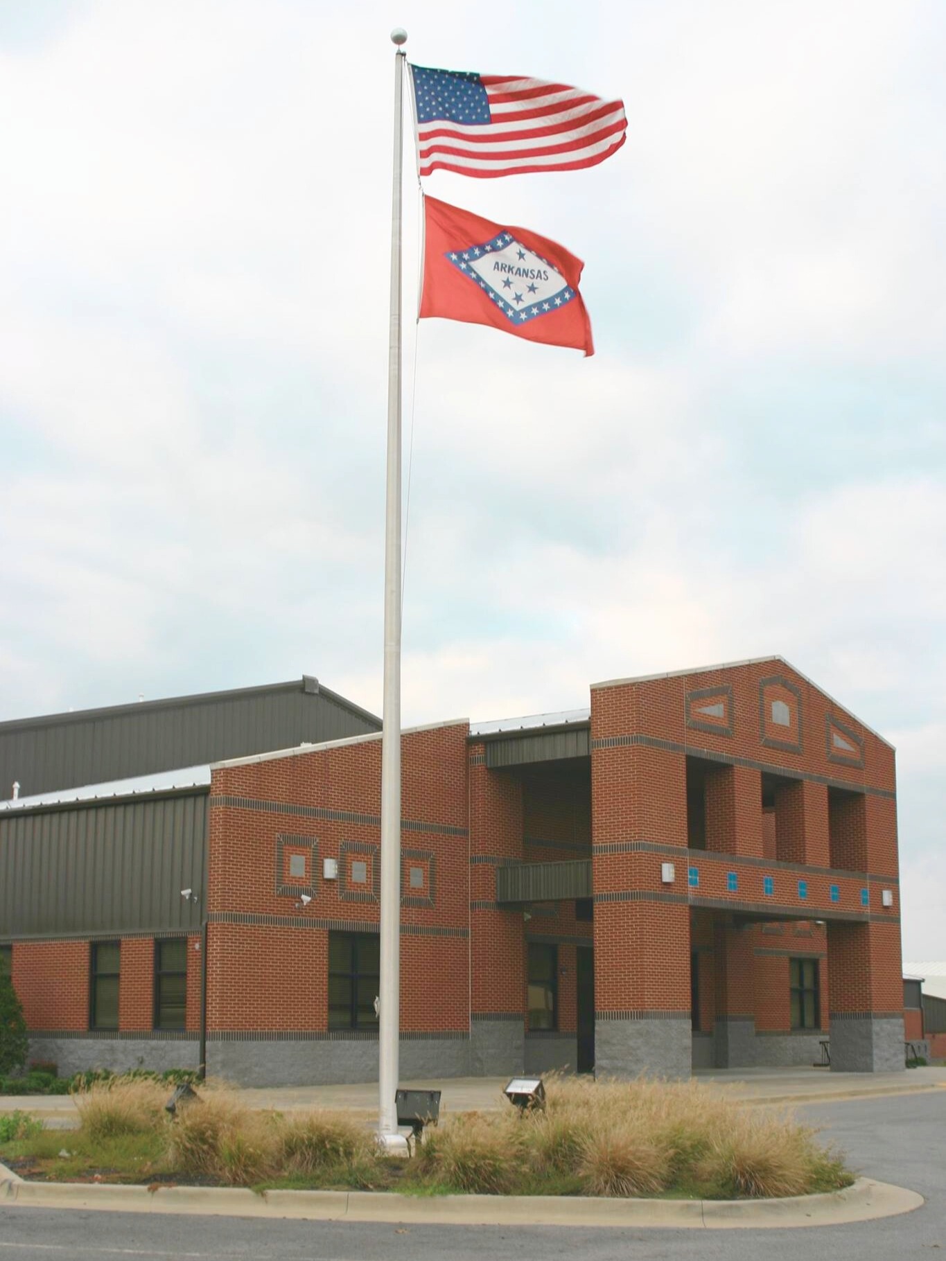 american flag and arkansas state flag outside of school